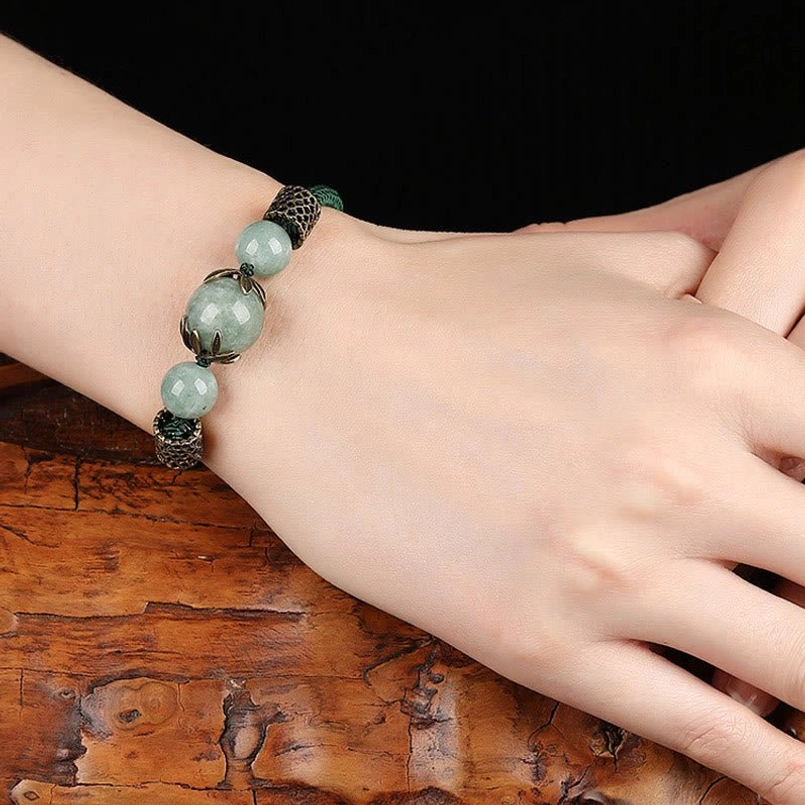 Adjustable green jade luck bracelet worn on woman's hand - natural jade stone styling
