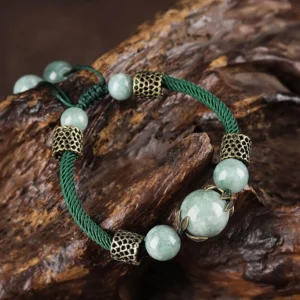 Handmade green jade prosperity bracelet with braided cord and bronze accents - overhead product shot
