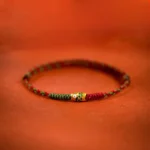 Green koi fish braided red string bracelet with gold charm, high angle view
