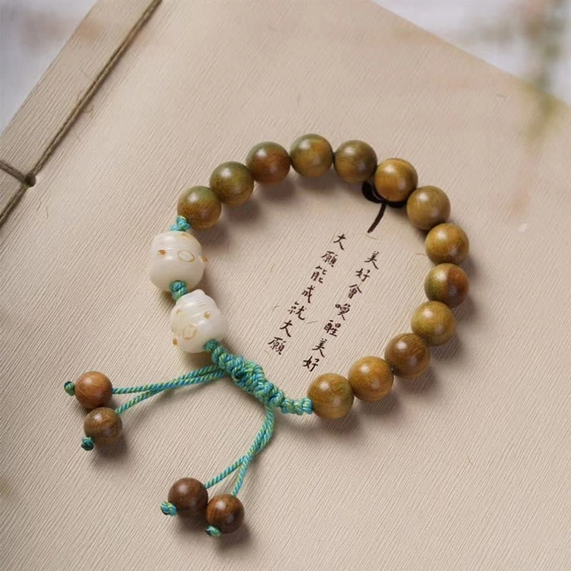 Handmade bodhi seed lucky cat bracelet with turquoise tassel on book