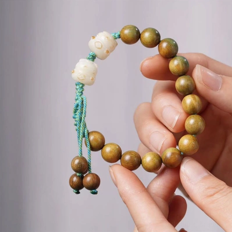 Close-up held green sandalwood bodhi seed lucky cat bracelet on wrist