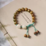 Green sandalwood lucky cat prosperity bracelet flat lay on vintage notebook