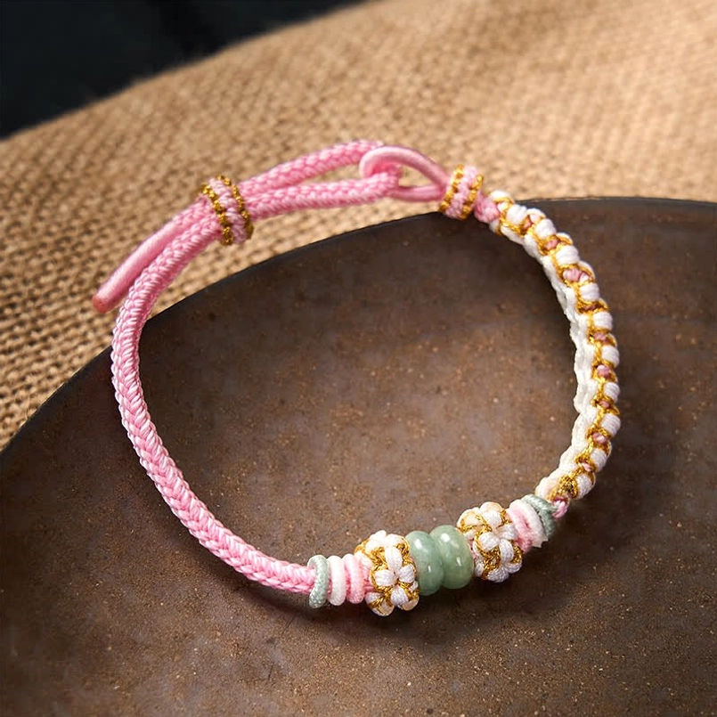 Green string luck bracelet showing peach blossom braiding and adjustable fit