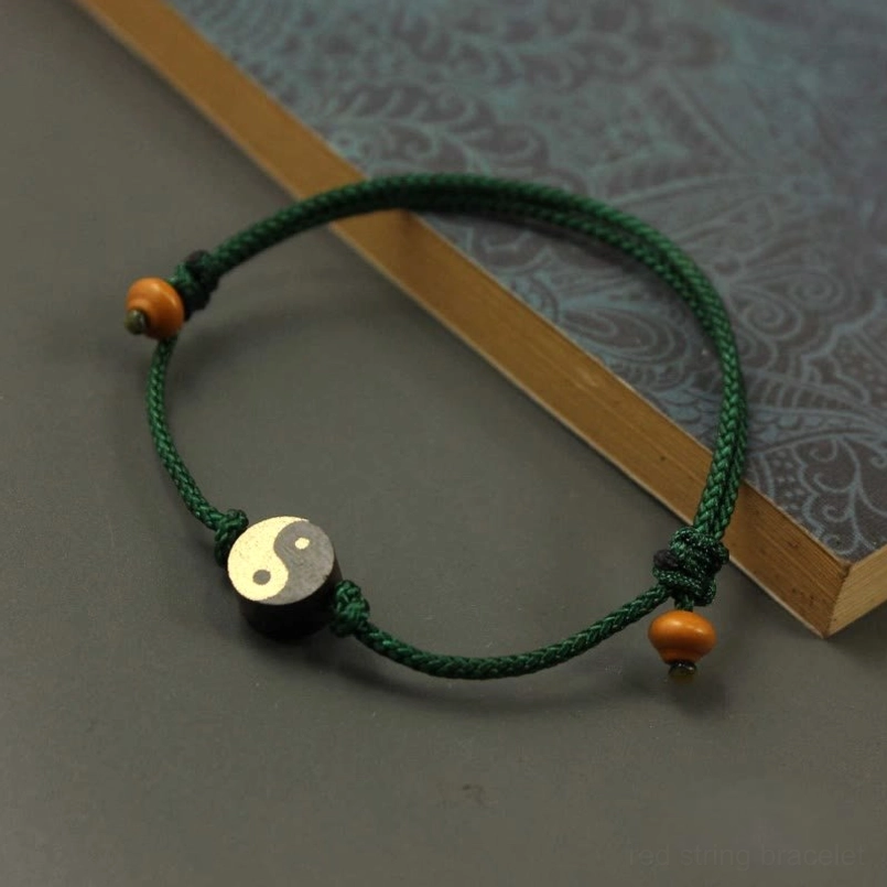 Green string Yin Yang bracelet with sliding knot on patterned background