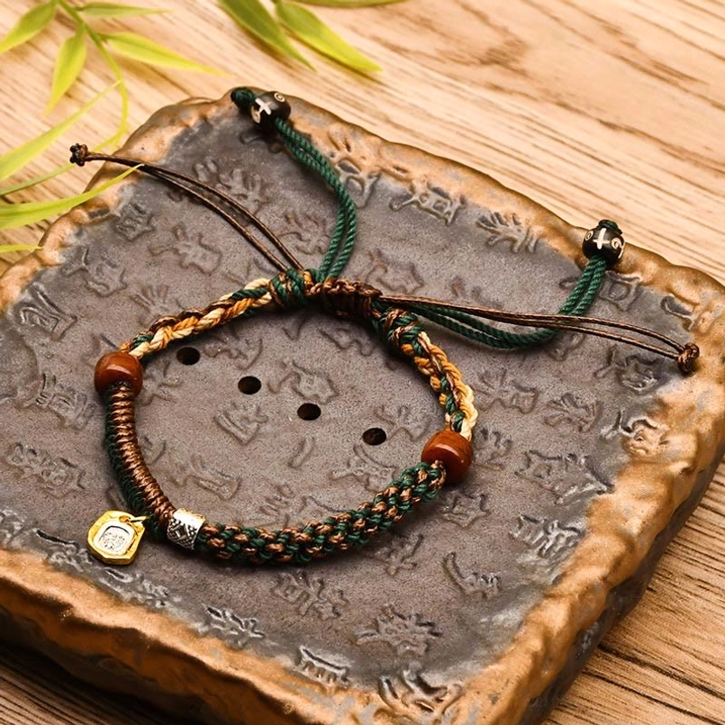 Green Tibetan braided Zakiram goddess of wealth red string bracelet on vintage stone tray
