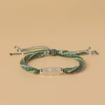 Green and white jade bamboo reincarnation knot red string bracelet with silver tassel beads, top-down view