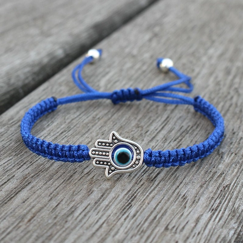 Hamsa evil eye blue string bracelet on wooden table - adjustable wrist talisman