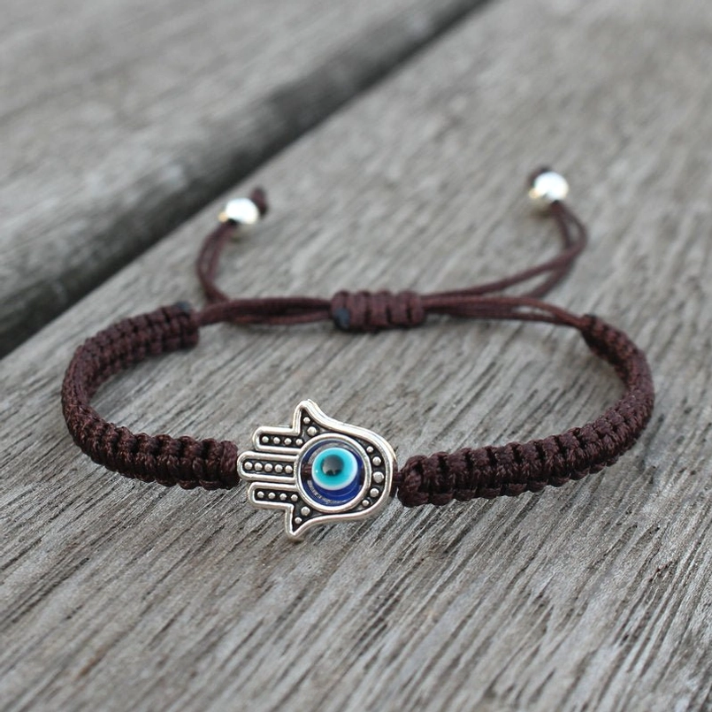 Hamsa evil eye brown string bracelet on wooden background - natural fiber talisman