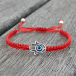 Hamsa evil eye red string protection bracelet on wooden surface - adjustable drawstring with silver beads
