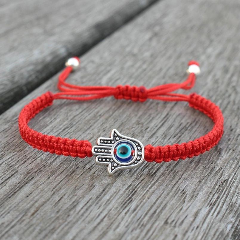 Hamsa evil eye red string protection bracelet on wooden surface - adjustable drawstring with silver beads