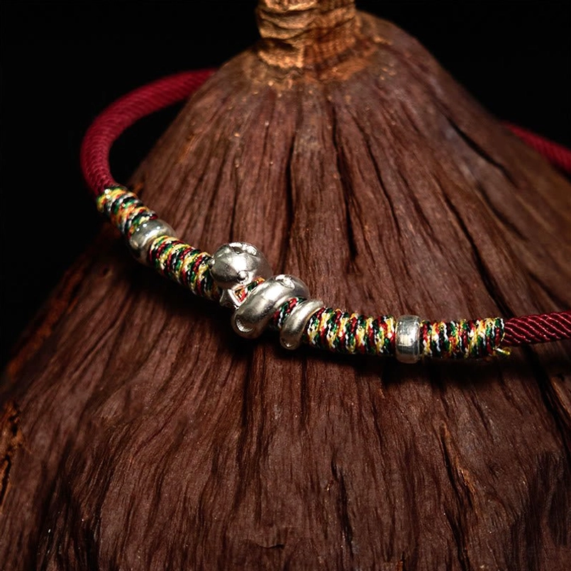 999 Sterling Silver Year of Snake Red String Bracelet side view on rough wood background