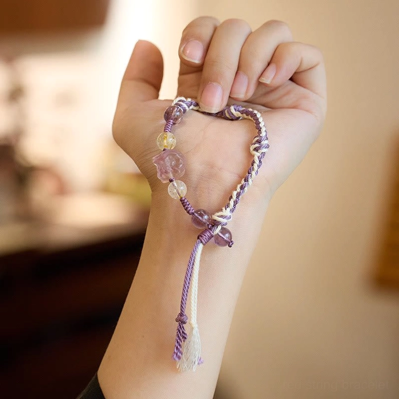 Hand held display of fluorite amethyst braided red string bracelet