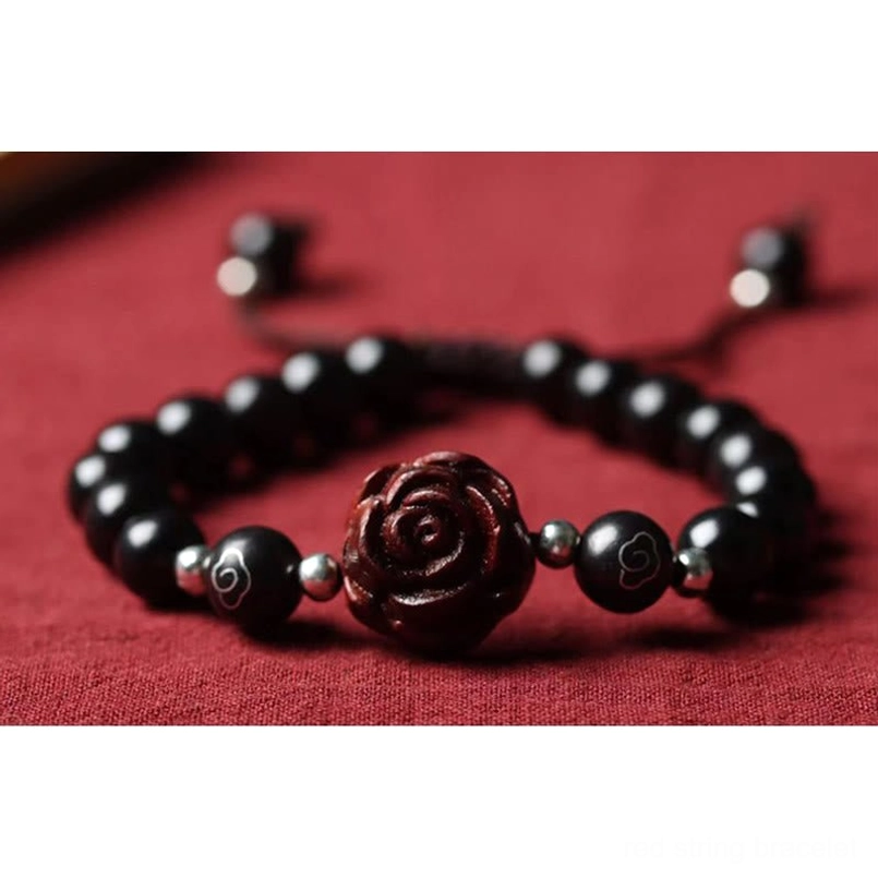Hand holding full small leaf red sandalwood bracelet on light wooden tabletop