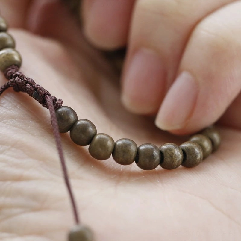 Close-up of hand holding woven red string copper bead bracelet on palm