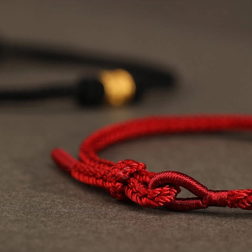 Close up of hand tied adjustable knots on Tibetan red string bracelet