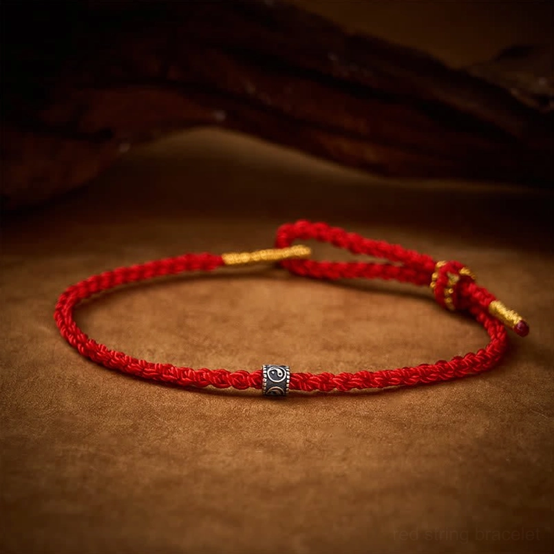 Hand-braided red string bracelet arranged in circle with silver Yin Yang symbol