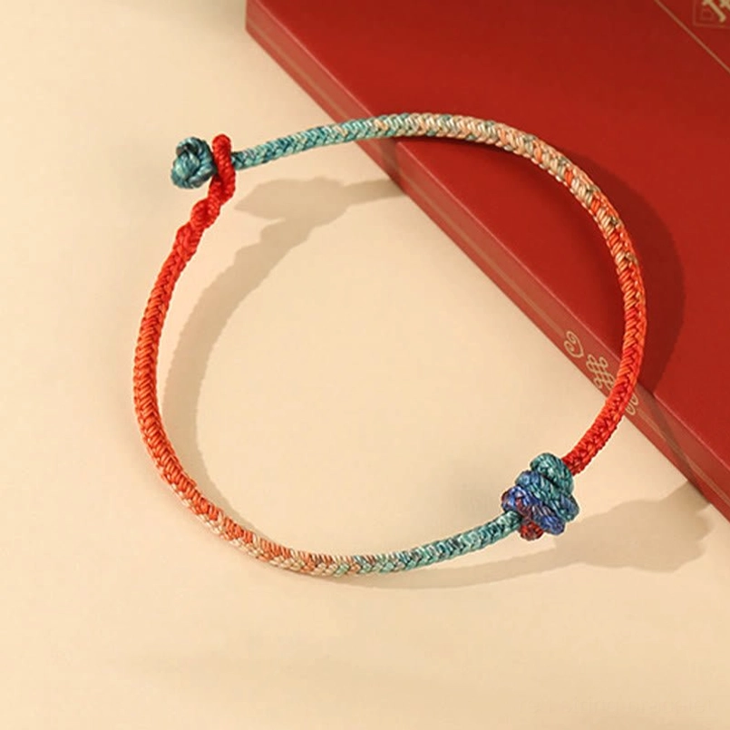 Adjustable red string bracelet with sliding knot detail and multicolor weave, top view