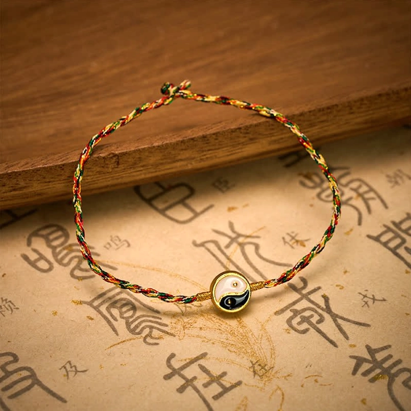 Multicolor braided red string Yin Yang tai chi bracelet with twisted woven texture on wood surface