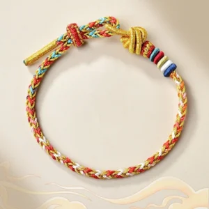 Handcrafted colorful Tibetan red string braided bracelet with gold accents on beige cloud background