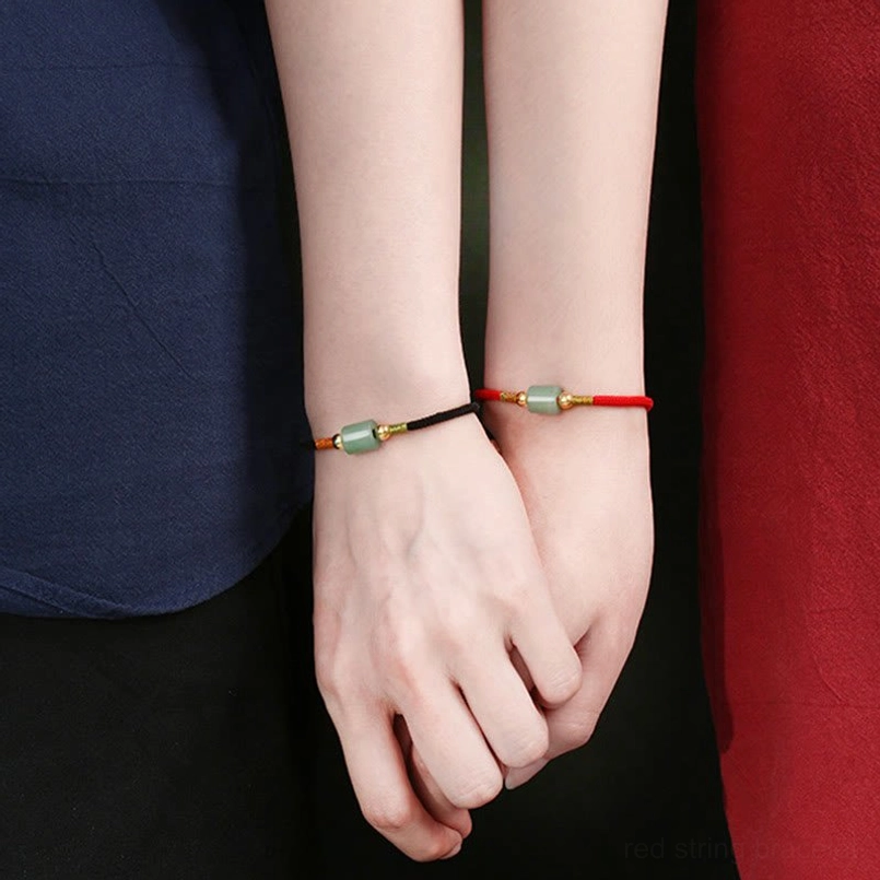 Handcrafted Tibetan red string bracelet with natural green aventurine stone on vintage tabletop