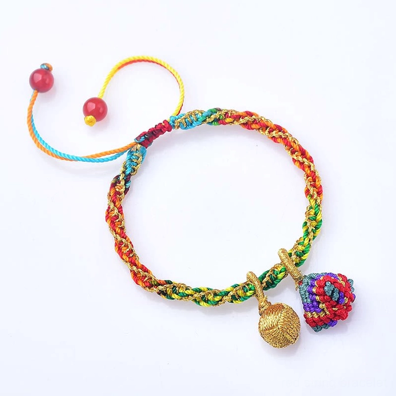 Flat lay of multicolor braided bracelet with zongzi pendants and dual red bead adjusters on green notebook