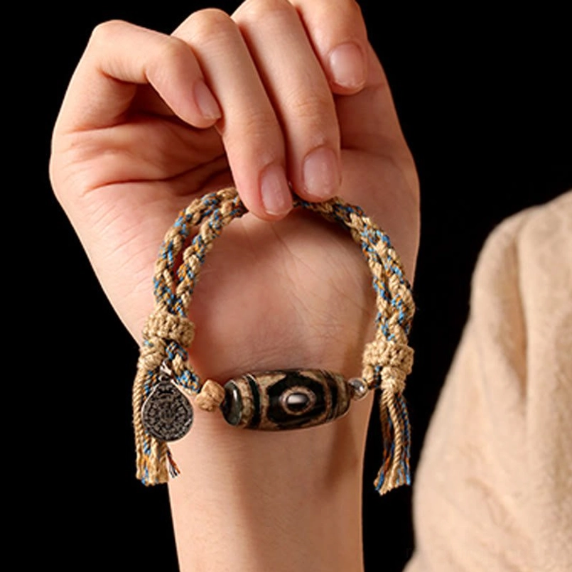 Close up front view of Tibetan Dzi Bead red string bracelet held in hands