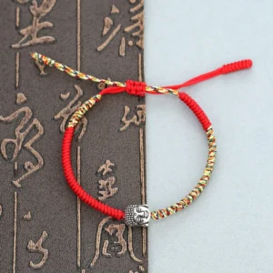Handmade Buddha head woven red string bracelet flat lay on Chinese calligraphy background
