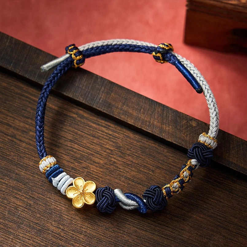 Handmade two-tone braided bracelet with gold four-leaf pendant and decorative knot details