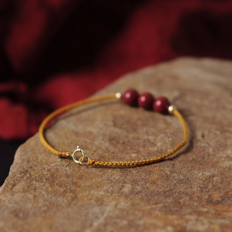 Hand woven cinnabar blessing bracelet oblique overhead view stone slab