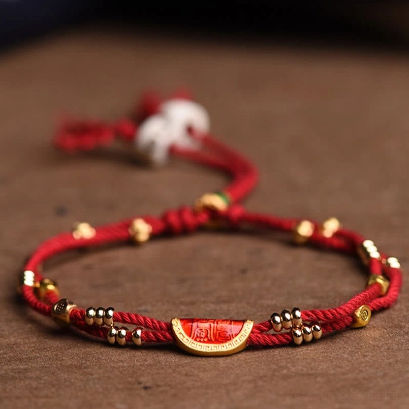 Handmade cinnabar dumpling red string bracelet closeup on brown wooden tabletop