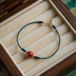 Handmade cinnabar red string blessing bracelet top view on wooden velvet jewelry tray