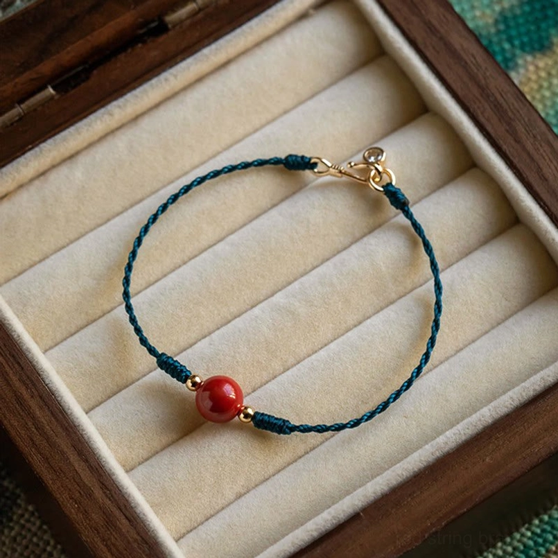 Handmade cinnabar red string blessing bracelet top view on wooden velvet jewelry tray