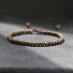 Handmade copper brass bead red string bracelet main view on dark grey stone tabletop