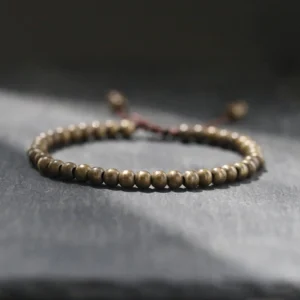 Handmade copper brass bead red string bracelet main view on dark grey stone tabletop