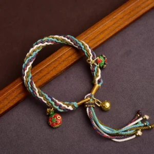 Handmade multicolor red string bracelet with golden Swallowing Beast charms on dark wood background