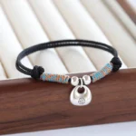 Black braided red string bracelet with 925 sterling silver Fu charm on wooden tray
