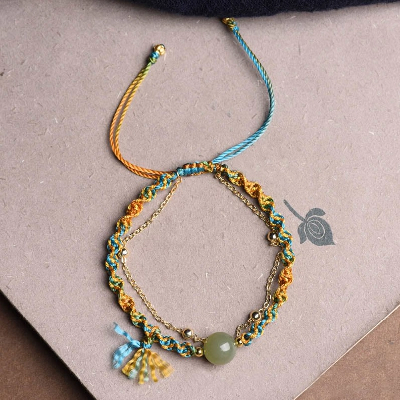 Close-up of woman wearing handmade jade lucky bracelet with tassel charm and metal accent