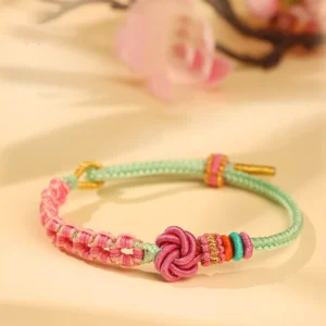 Handmade pink green peach blossom knot braided red string bracelet top view