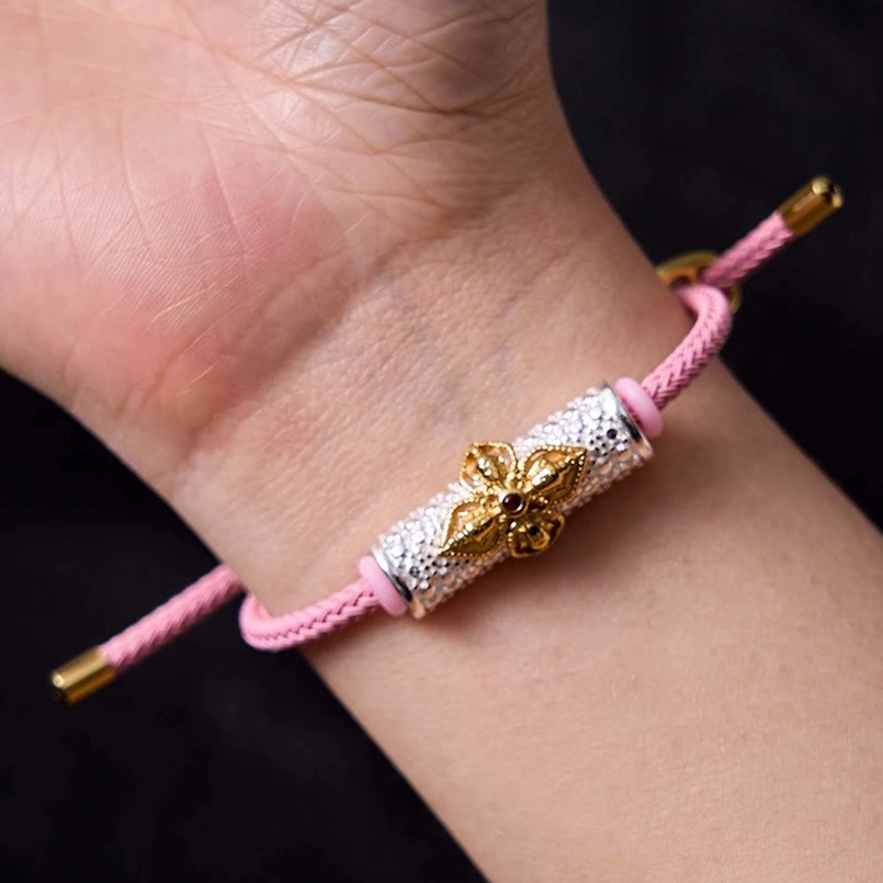 Handmade pink string luck bracelet with ornate silver gold flower bead charm