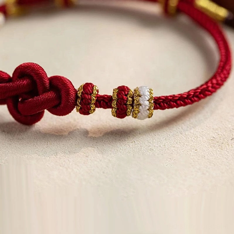 Handmade red string bracelet side view with woven rope and decorative gold-white beaded trim