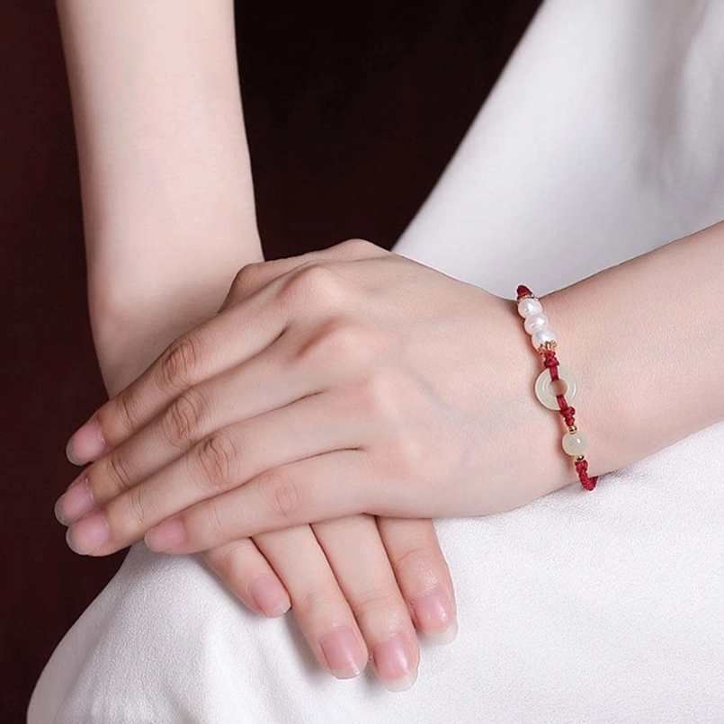 Red string beaded jade and pearl bracelet worn on hand close up