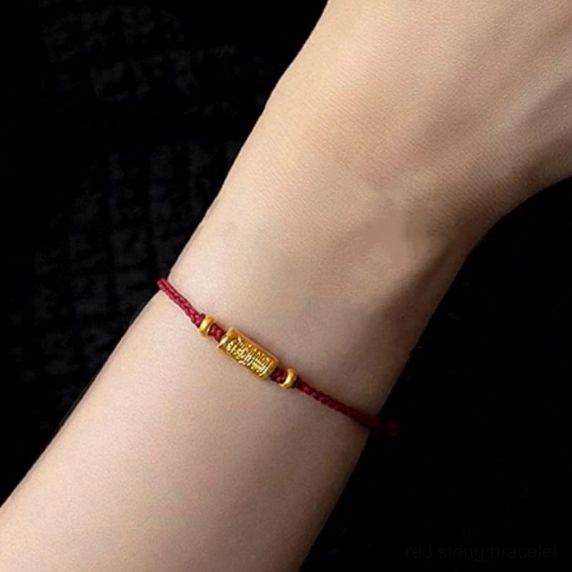 Red braided string bracelet with gold engraved barrel amulet - wrist display