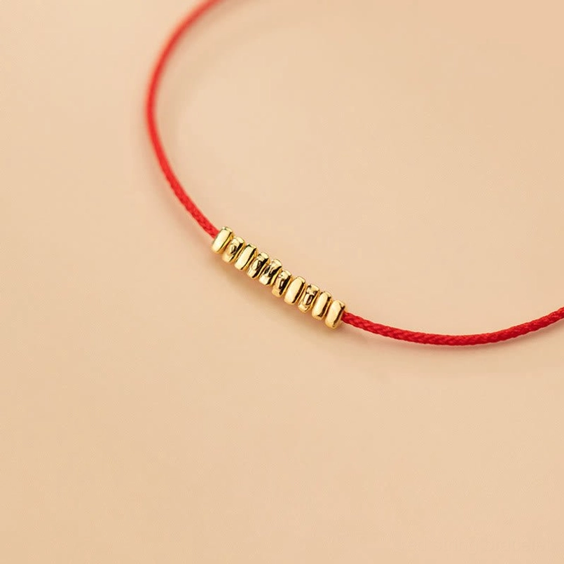 Sterling silver red rope bracelet with gold accents displayed on neutral background
