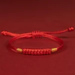 Handmade braided red string lucky knot bracelet side top view on red background