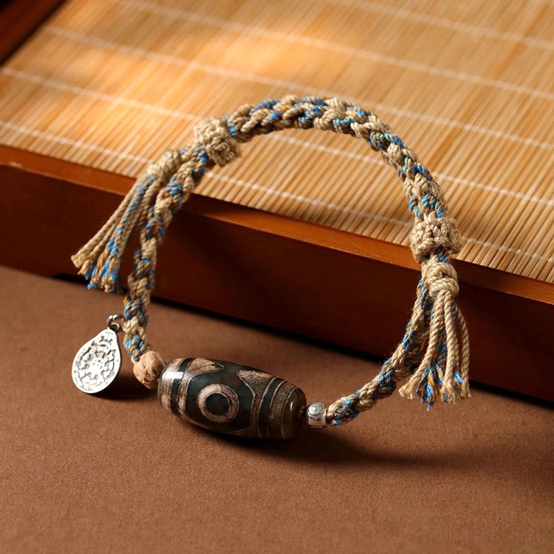 Top side view of handmade Tibetan Dzi Bead red string bracelet on bamboo wooden table