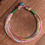 Handmade Tibetan five color red string protection bracelet flat lay on wooden table