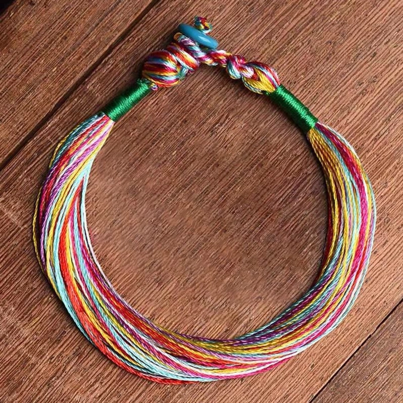 Handmade Tibetan five color red string protection bracelet flat lay on wooden table