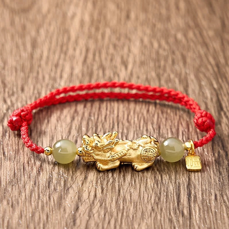 Tightly braided red cord Pi Xiu bracelet on light wood grain tabletop top view