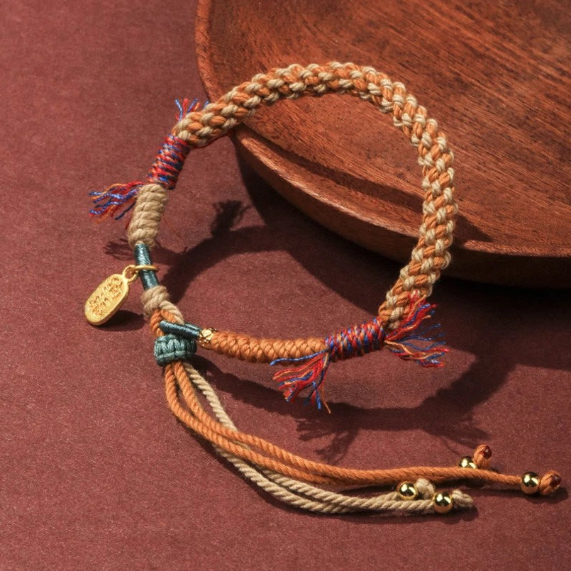 Coiled Tibetan red string bracelet with adjustable tassels and gold Fu pendant