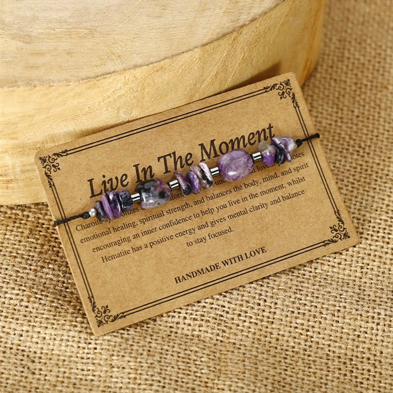 Red string bracelet with charoite and hematite stones showcased on natural burlap background